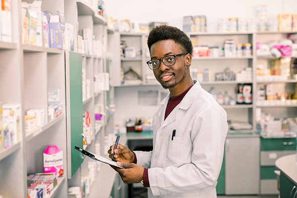 man standing in pharmacy holding tablet